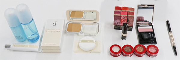 写真：ガイドメイクで使用するコスメ(左からDプログラムの化粧水・乳液・化粧下地・ファンデーション・パフ、インテグレートのクリームアイシャドウ（トゥインクルバームアイズ：ピンク・薄茶色・濃茶・白）、マキアージュリップ6色（ドラマティックエッセンスルージュ）、チーク、マキアージュアイブローペンシル（ダブルブロークリエーター）